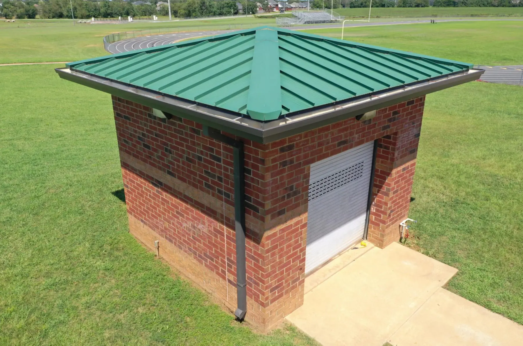 Close-up aerial of a brick utility building with a green metal roof
